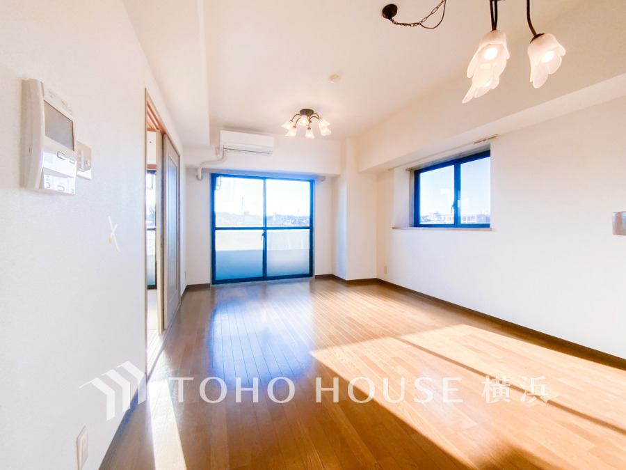 陽光が差し込む明るいリビング。バルコニーと窓から爽やかな風が通り抜ける快適な空間です。