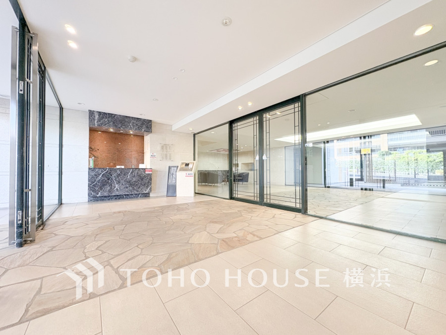 明るく開放的なエントランスホール。石調の床と大理石の受付カウンターが高級感を演出します。