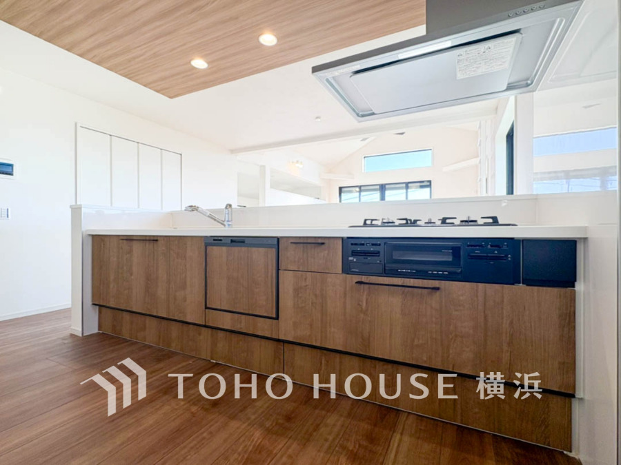 木目調の収納と白い天板が調和した、明るく開放的な対面キッチンです。快適な調理空間を実現します。