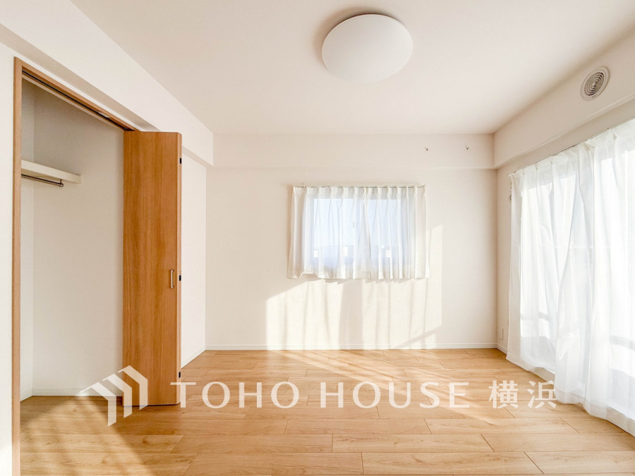 バルコニーから明るい自然光が差し込む洋室。大型クローゼット付きで収納も充実しています。
