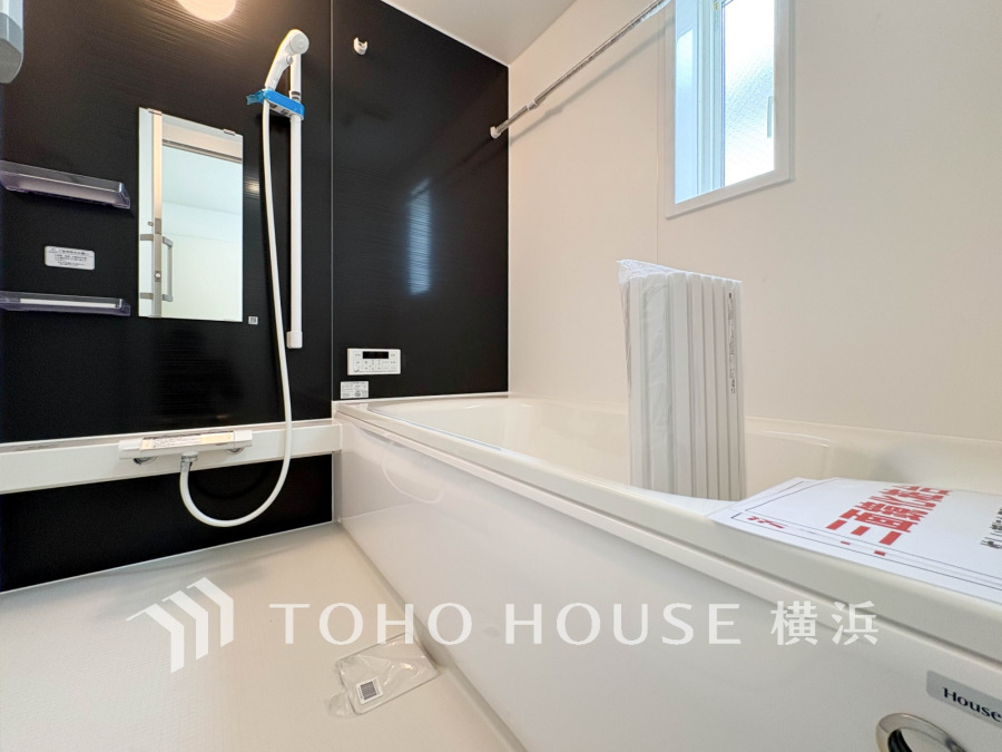 シックなブラックの壁面と白を基調とした清潔感あふれる浴室。窓から自然光も差し込みます。