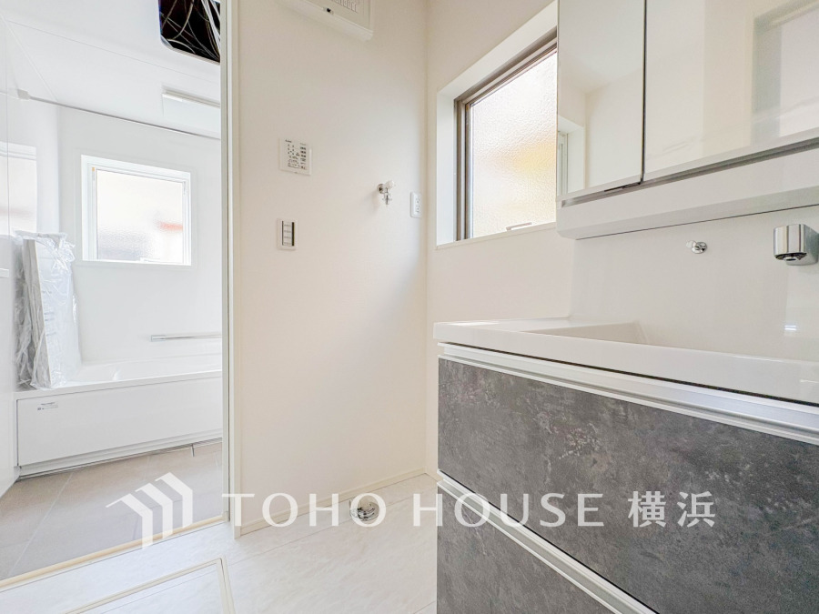 清潔感あふれる洗面室とバスルーム。自然光が入り、明るく快適な空間が広がります。収納も充実しています。