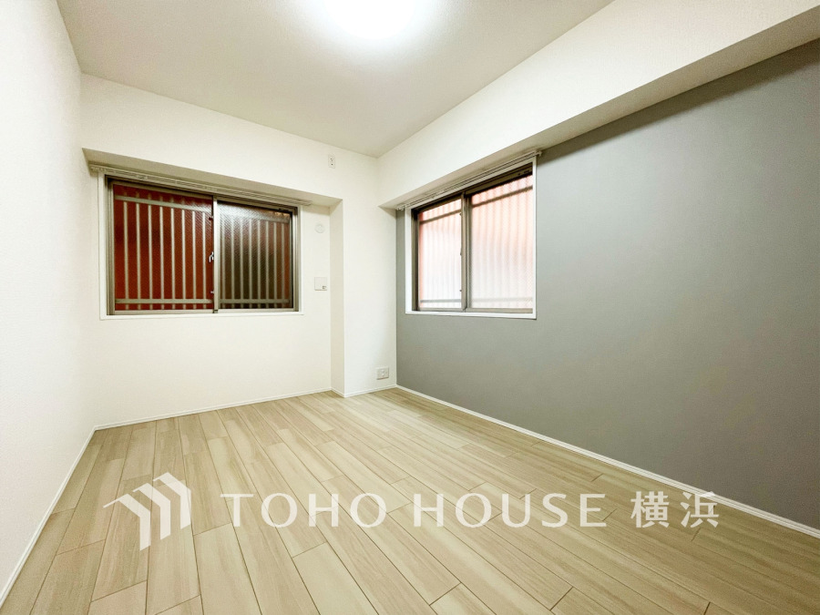 落ち着いたグレーのアクセントクロスが映える、明るくシンプルな洋室。