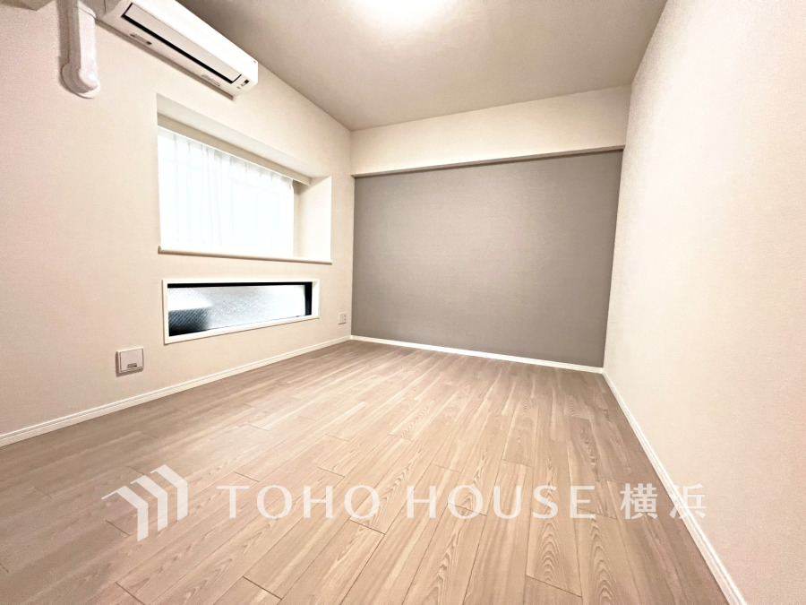 明るい自然光が差し込む、シンプルで落ち着いた色合いの洋室。エアコン完備で快適な空間です。