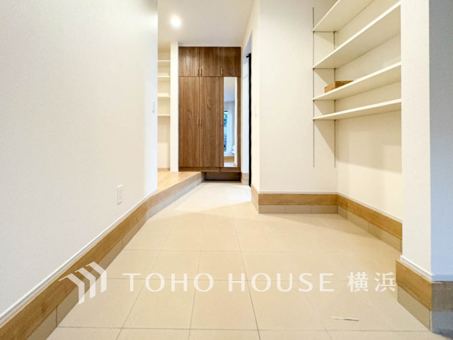 広々とした玄関ホールには、収納力の高いシューズボックスと壁面収納が設置され、すっきりとした空間を実現。