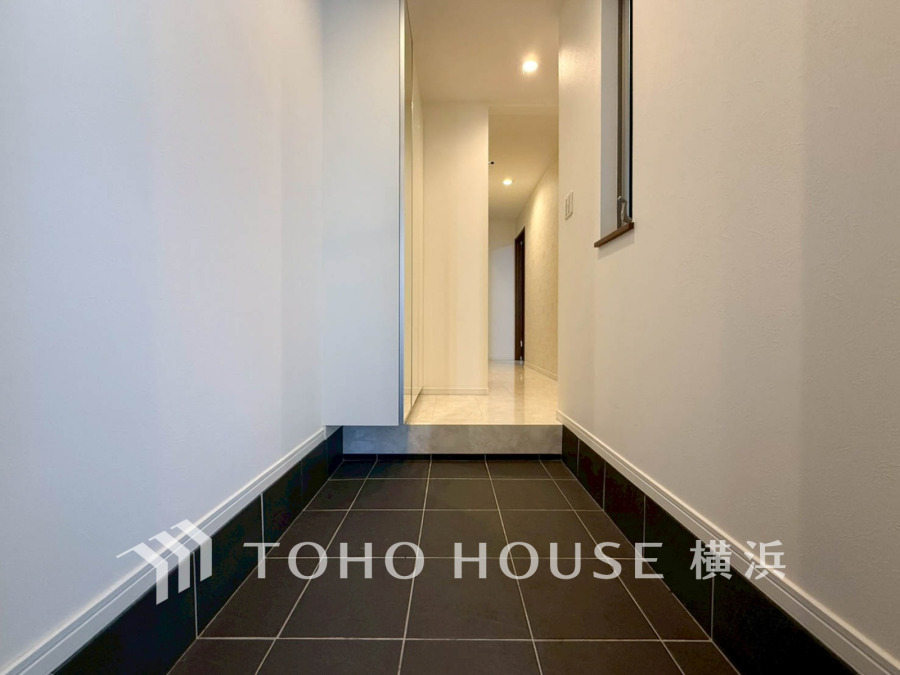 シンプルで清潔感のある玄関。黒タイルが空間を引き締め、広さと明るさを両立しています。