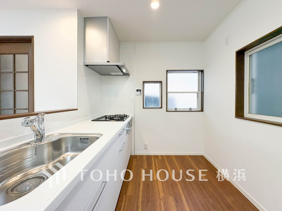 清潔感あふれる白を基調としたキッチン。窓からの自然光で明るく、効率的に調理ができる快適な空間です。