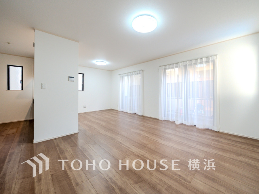 明るい自然光が差し込む広々としたリビング。シンプルな白壁と木目調フローリングが落ち着く空間を演出します。