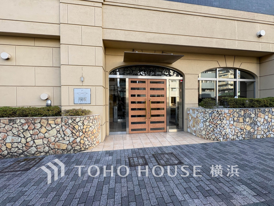 落ち着いた色調の外観と石張りの植え込みが調和する、上品なマンションのエントランスです。