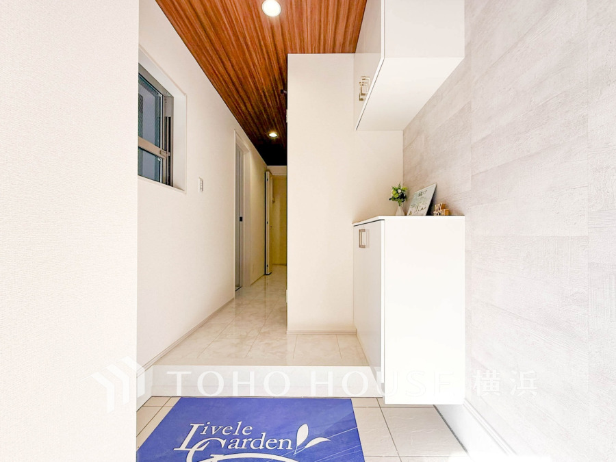 木目天井と白を基調にした清潔感あふれる玄関。収納スペースも充実し、すっきりとした印象です。