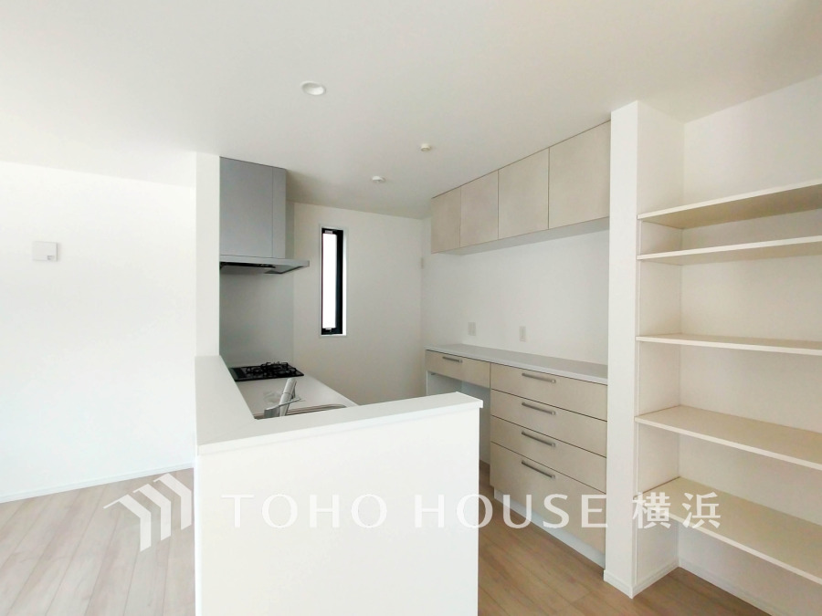 収納棚を背面に設置した統一感のあるキッチンスペースは美しく、機能性も良好です。
