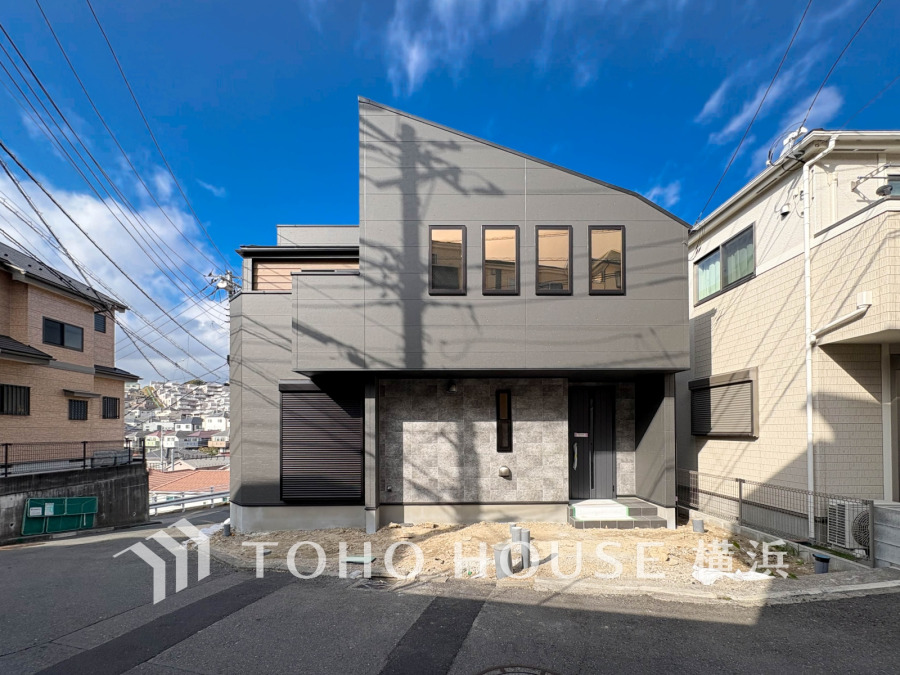 青空に映える、洗練されたモダンな外観デザインの邸宅。特徴的な斜め屋根が個性を際立たせ、高台からの開放的な眺望が家族の毎日を豊かにします。