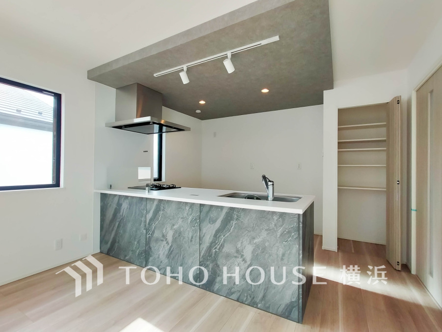 高級感ある大理石調のカウンターキッチンと収納豊富なパントリー付きのキッチンスペース。