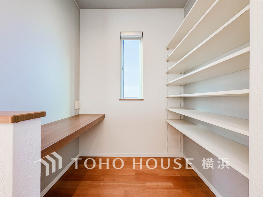 収納力抜群の可動棚と作業カウンター付きの多目的スペース。明るい窓から自然光が差し込み快適です。