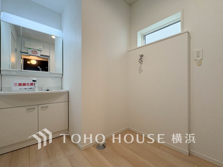 三面鏡付き洗面台と洗濯機置き場を備えた明るく清潔感のある洗面室です。小窓で自然光も取り入れます。