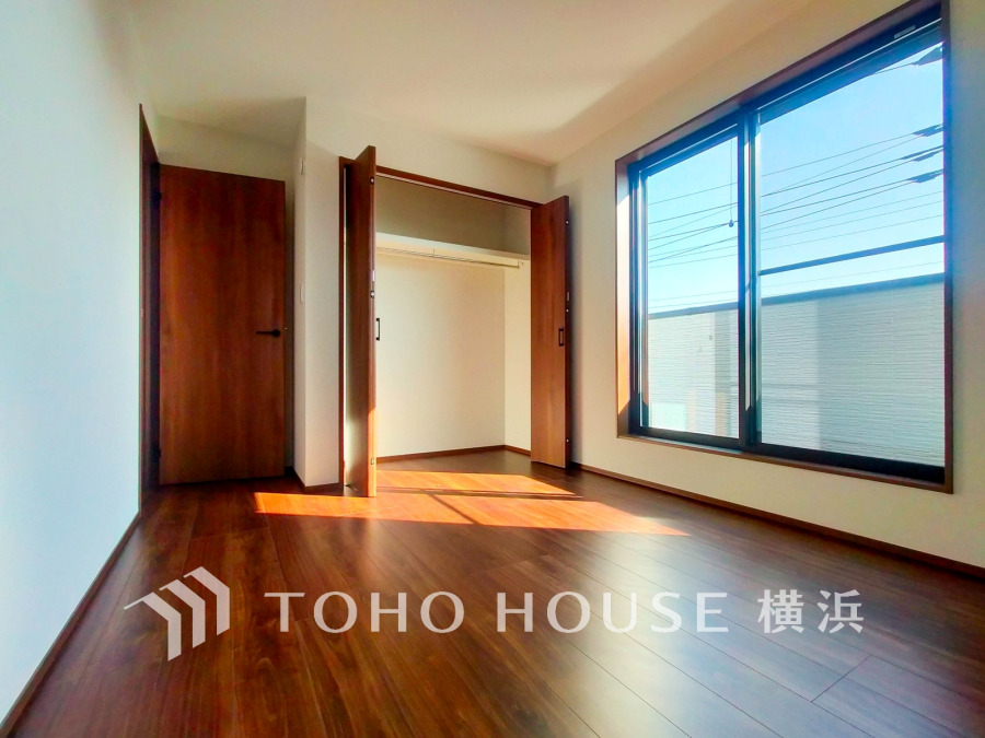 明るい陽射しが差し込む、広々とした収納付きの洋室。落ち着いた木目調フローリングが温かみを演出します。