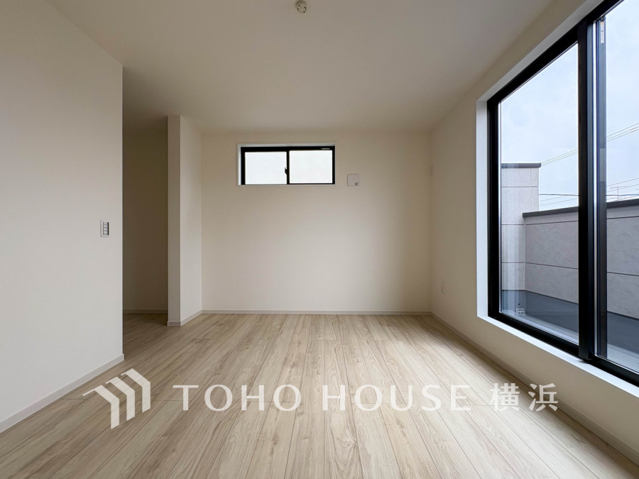 大きな窓から自然光が差し込む明るく開放的な洋室。シンプルな内装で多用途に対応可能です。