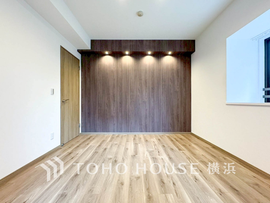 落ち着いた木目調のアクセントウォールが印象的な、明るく開放感のあるシンプルな洋室です。