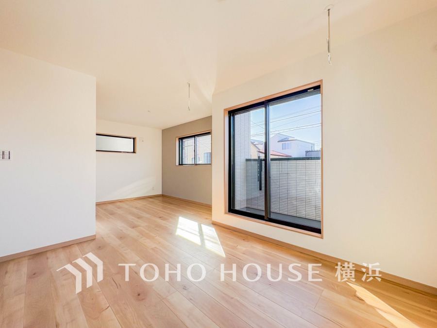 陽光が差し込む明るいリビング。木目調のフローリングと白壁で温かみのある空間が広がります。