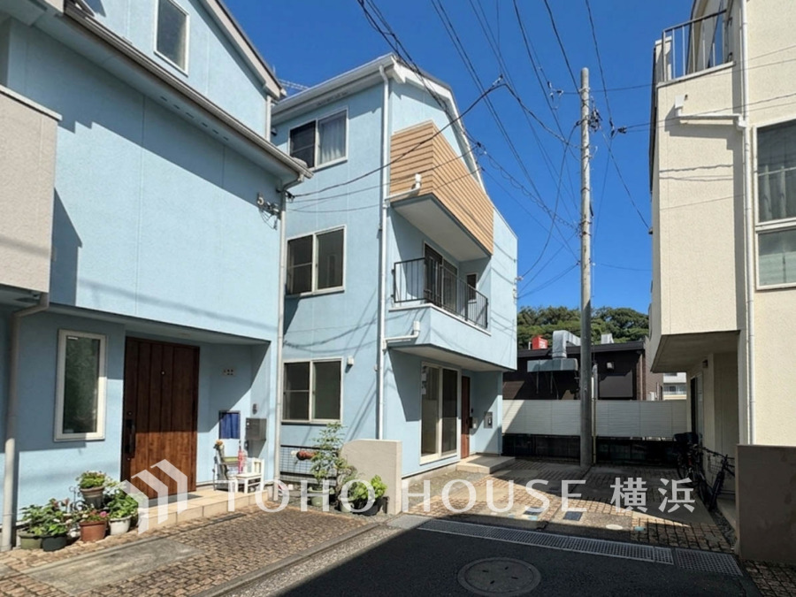 明るいブルーの外壁が印象的な3階建て住宅。閑静な住宅街に位置し、駐車スペースも確保されています。