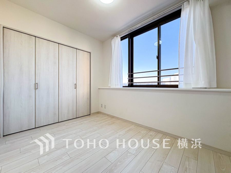 大きな窓から明るい光が差し込む、収納充実のシンプルで清潔感ある洋室です。