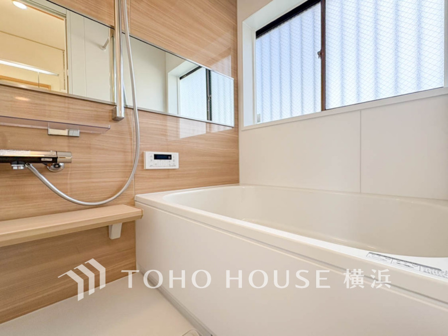 木目調の壁が温かみを演出する、明るく広々とした浴室。大きな窓で換気も快適です。