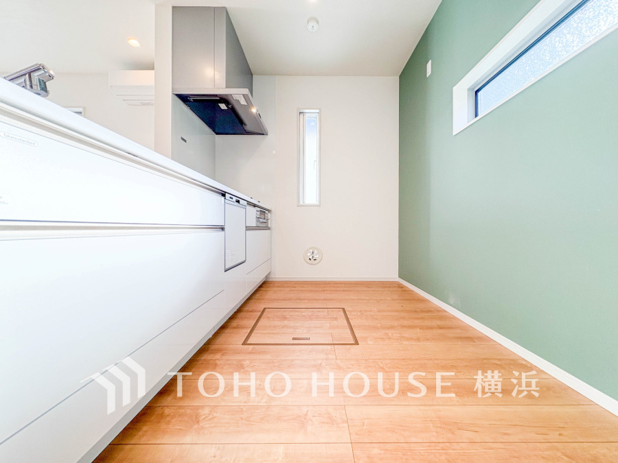 グリーンのアクセントクロスが映える、明るく清潔感のあるシステムキッチン。収納も充実しています。