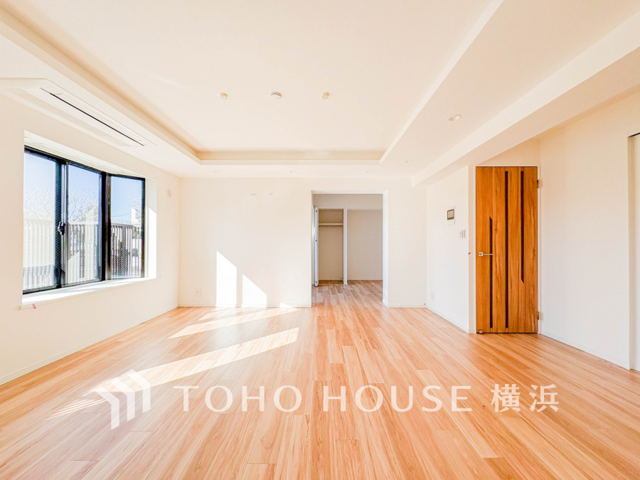 陽光が差し込む広々としたリビング。木目調のフローリングと白い壁で明るく温かみのある空間です。