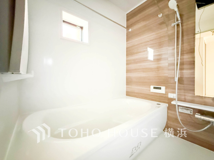 木目調のアクセント壁が温かみを添える、明るく清潔感のあるバスルームです。ゆったりとした浴槽でリラックスできます。