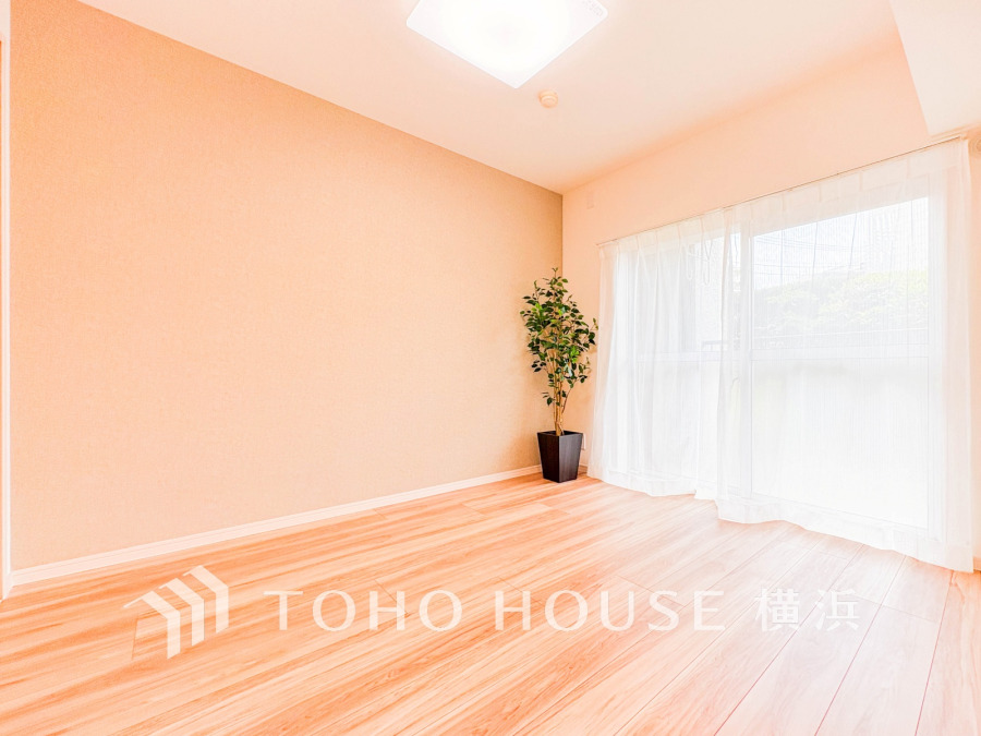 明るい自然光が差し込むシンプルで清潔感のある居室。ナチュラルな床材とアクセント壁が温かみを演出します。