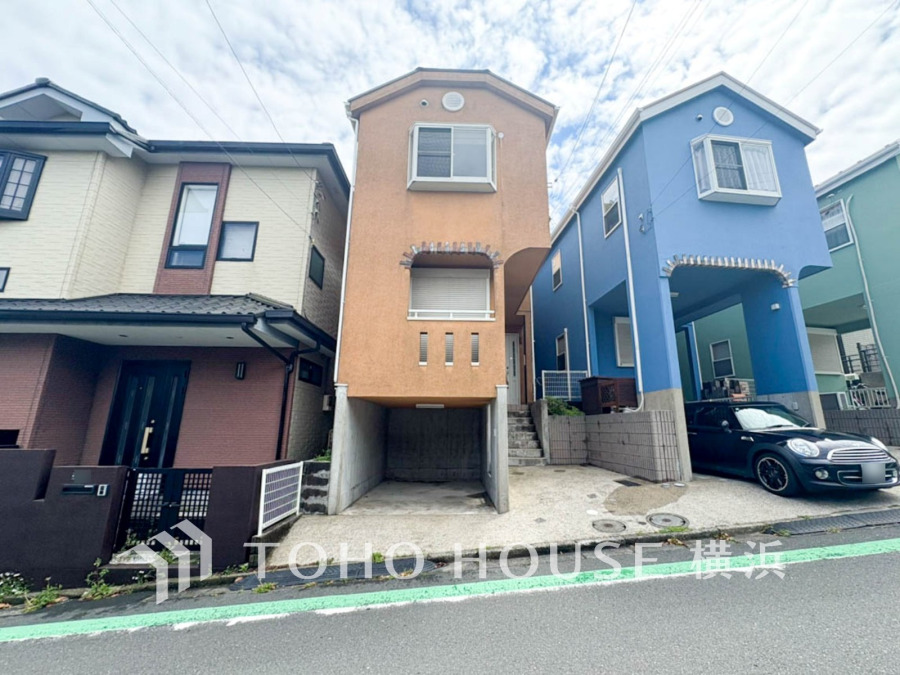 個性的な外観が魅力の3階建て住宅。1階は駐車スペースで、狭小地を有効活用した設計です。
