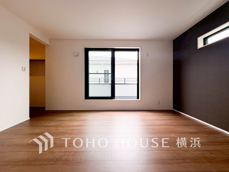 落ち着いた木目フローリングとアクセントクロスが調和する、明るく開放的なリビング空間です。