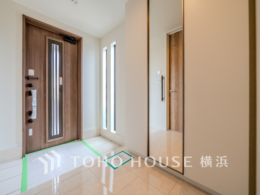 自然光が差し込む明るい玄関。便利な大型のミラーのついたシューズボックスを設置しています。