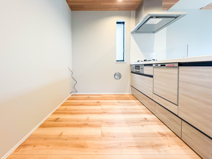 明るく清潔感のある木目調キッチン。広々とした床スペースで快適な調理環境を実現しています。