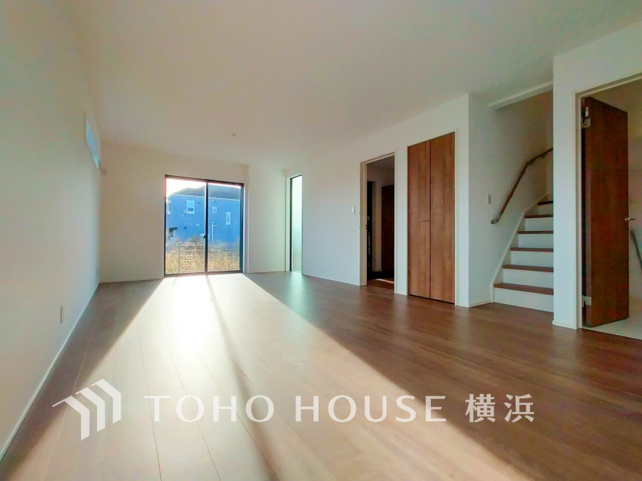 陽光が差し込む広々としたリビング。木目調フローリングと白壁で温かみと開放感を演出しています。