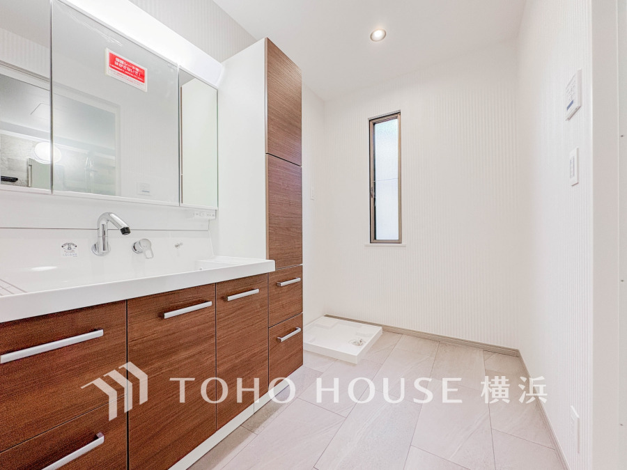 木目調キャビネットと大きな鏡が特徴の洗面スペース。明るく清潔感あふれる空間で、収納も充実しています。