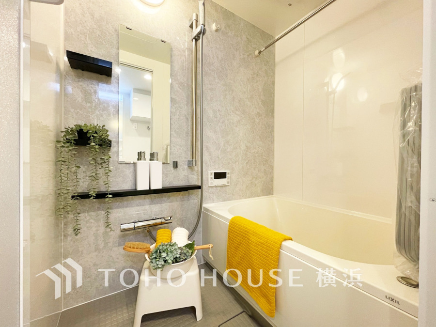 明るく清潔感のあるバスルーム。機能的なシャワー設備と収納棚で快適な入浴時間を実現します。