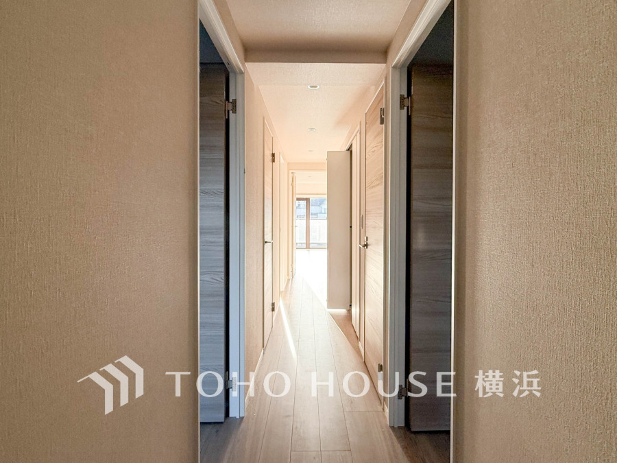 明るい自然光が差し込む、シンプルで清潔感のある廊下。両側に複数の扉が並ぶ機能的な間取りです。