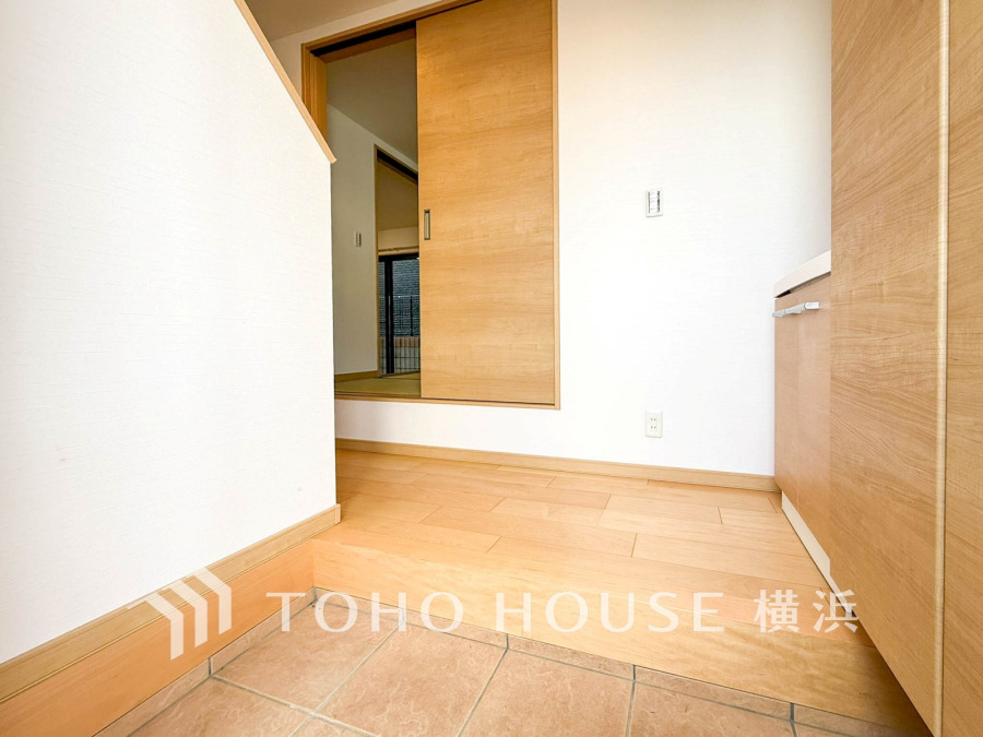 明るい木目調の玄関は、タイルとフローリングの段差で空間をすっきりと分けた設計です。