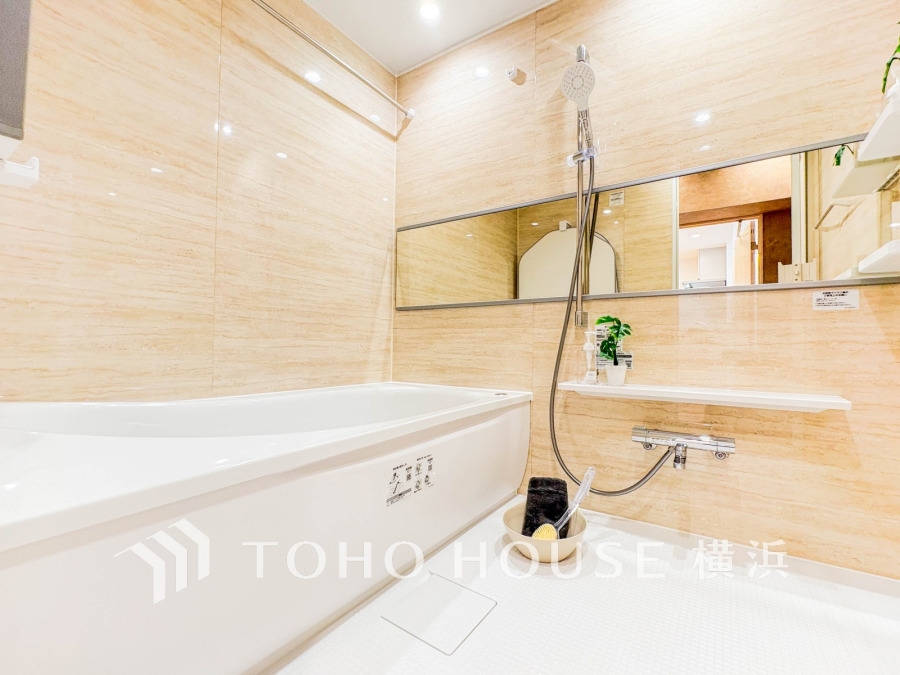 清潔感あふれるベージュの壁と広々とした浴槽が魅力の、快適でリラックスできるバスルームです。