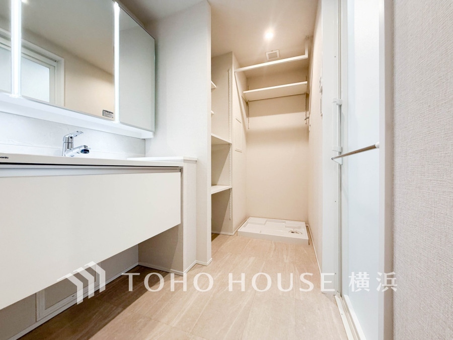 清潔感あふれる洗面スペース。収納棚と洗濯機置き場があり、使い勝手の良い機能的な設計です。