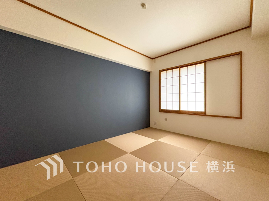 落ち着いた紺色のアクセントクロスと障子窓が調和する和モダンな畳の和室です。