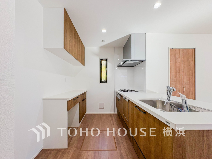 木目調の収納とバックカウンターが調和した、使い勝手の良い明るいシステムキッチンです。