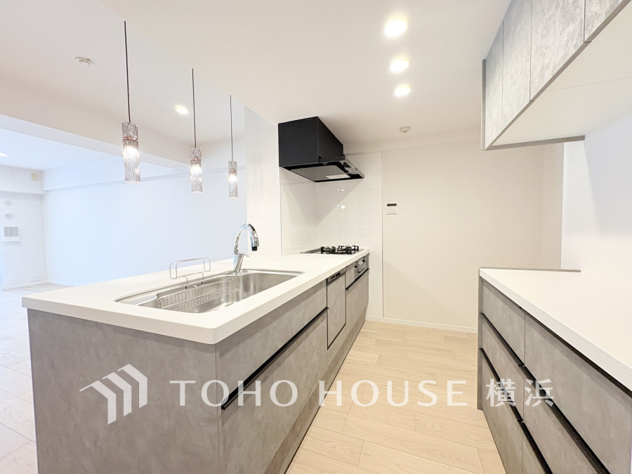 スタイリッシュなグレーの対面キッチン。収納棚を背面に設置した統一感のあるキッチンスペースです。
