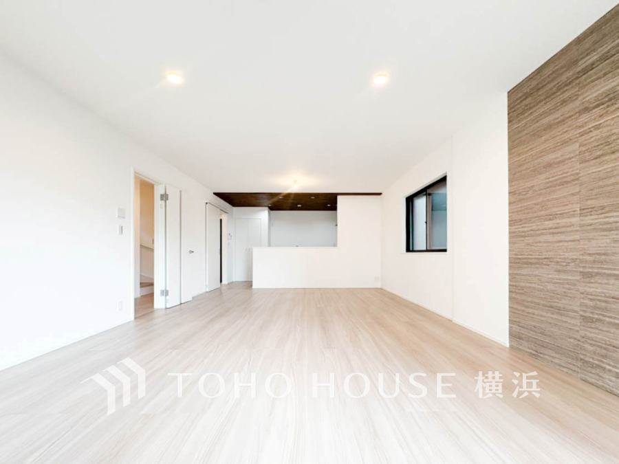 明るい自然光が差し込む、開放感あふれるリビングスペース。木目調のアクセント壁がおしゃれな空間を演出。