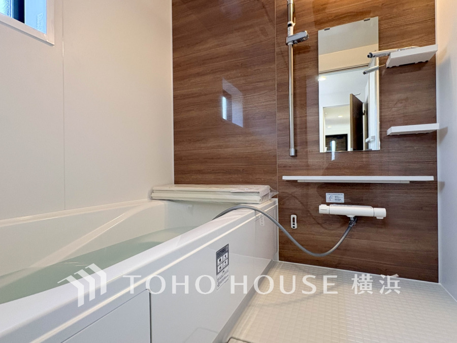 木目調の壁が温かみを与える、清潔感あふれる最新設備のバスルームです。快適なバスタイムを実現します。