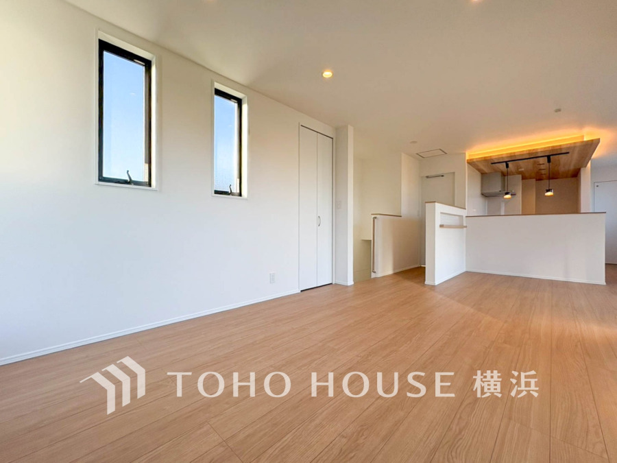 明るい自然光が差し込む広々としたリビング。木目調の床と温かみのある照明が居心地の良さを演出します。