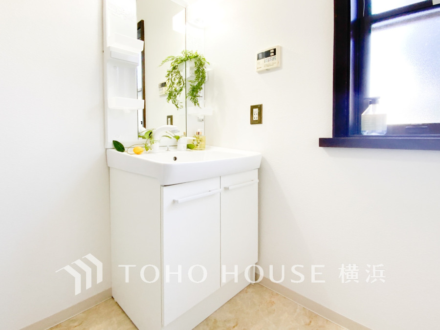 清潔感あふれる白基調の洗面台。窓からの自然光で明るく、快適な身支度スペースを実現しています。