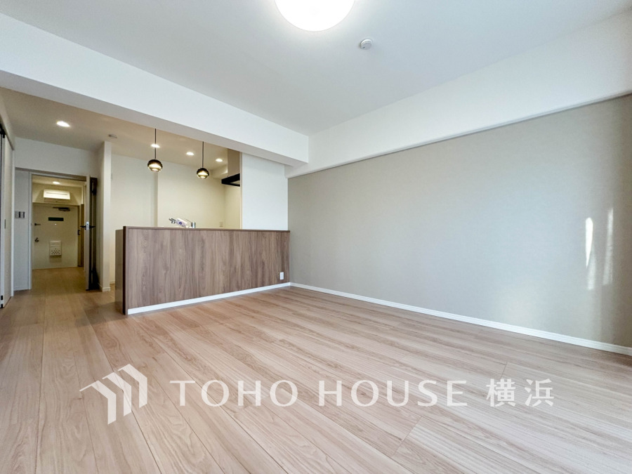 明るい自然光が差し込む、木目調の床とアクセントクロスが美しいリビングダイニングです。