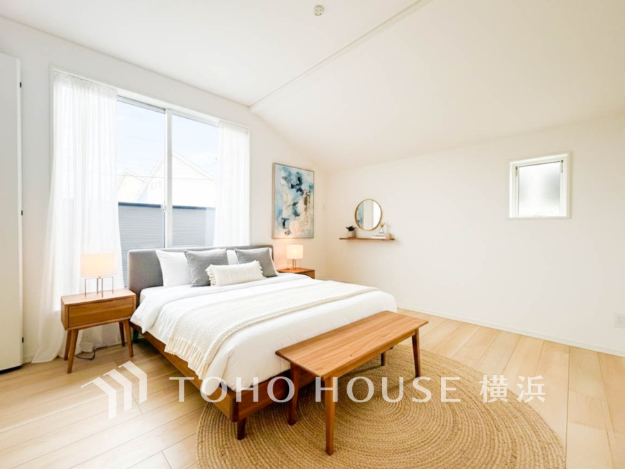 自然光がたっぷり入る明るい寝室。木の温もりを感じる家具とシンプルなインテリアで落ち着いた空間を演出しています。（家具はAI加工です）